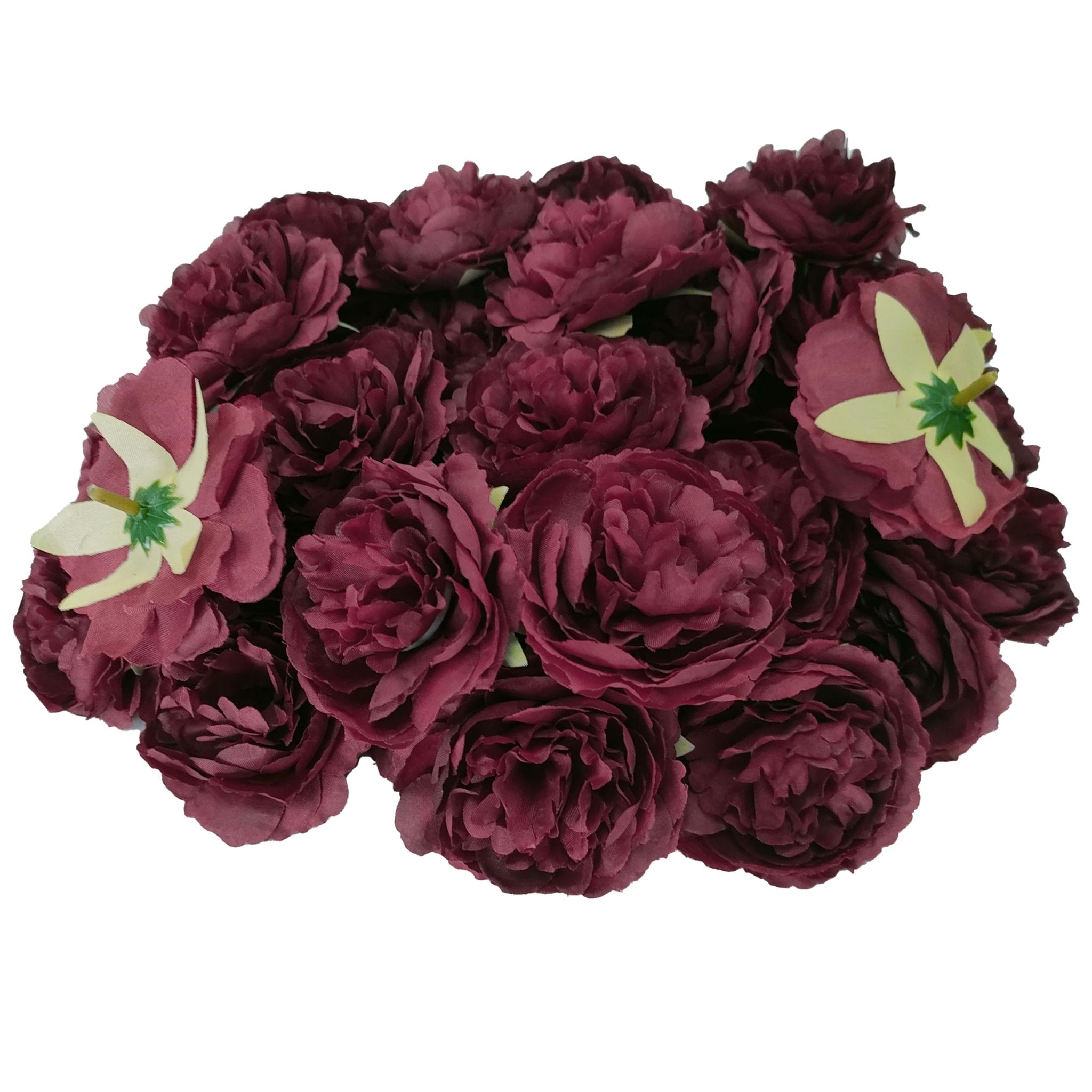 Pile of burgundy silk rose heads with green and yellow centers, viewed from above.