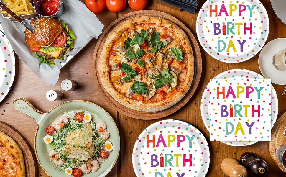 Overhead view of a birthday party table setting with pizza, burger, salad, and polka dot plates and napkins.