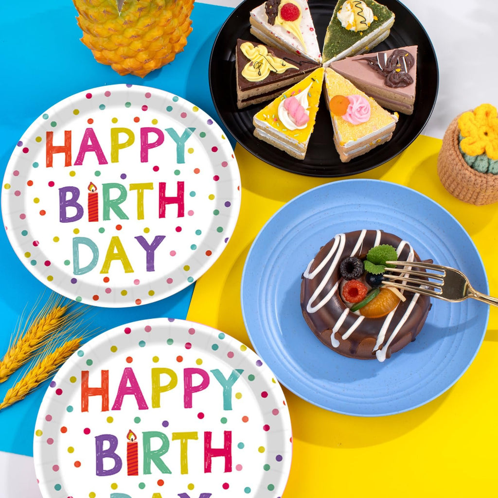 Two paper plates with colorful 'Happy Birthday' text and polka dots, next to slices of cake and a donut.