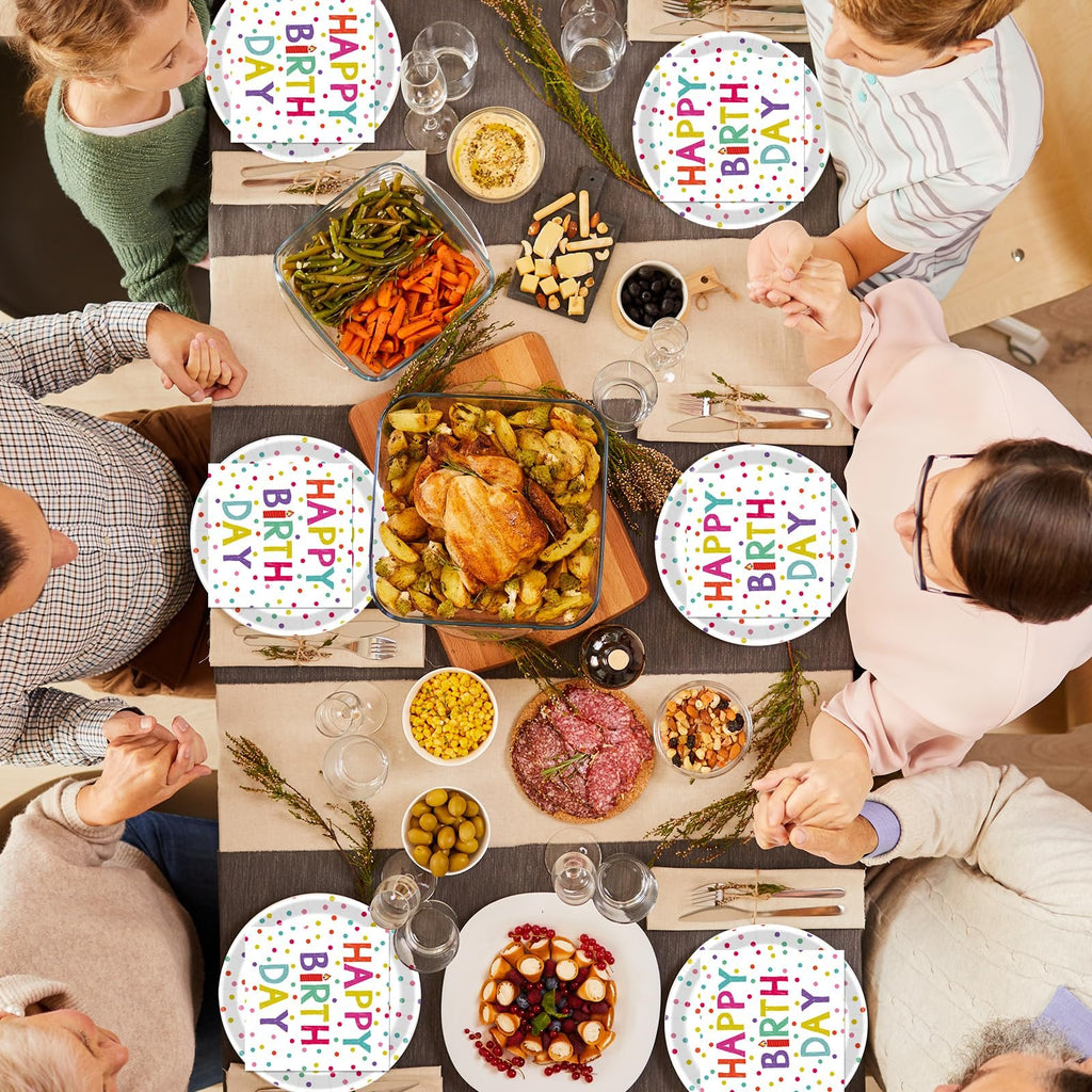 Overhead view of a family gathered around a table for a birthday meal, with plates and napkins featuring colorful polka dots and 'Happy Birthday' text.