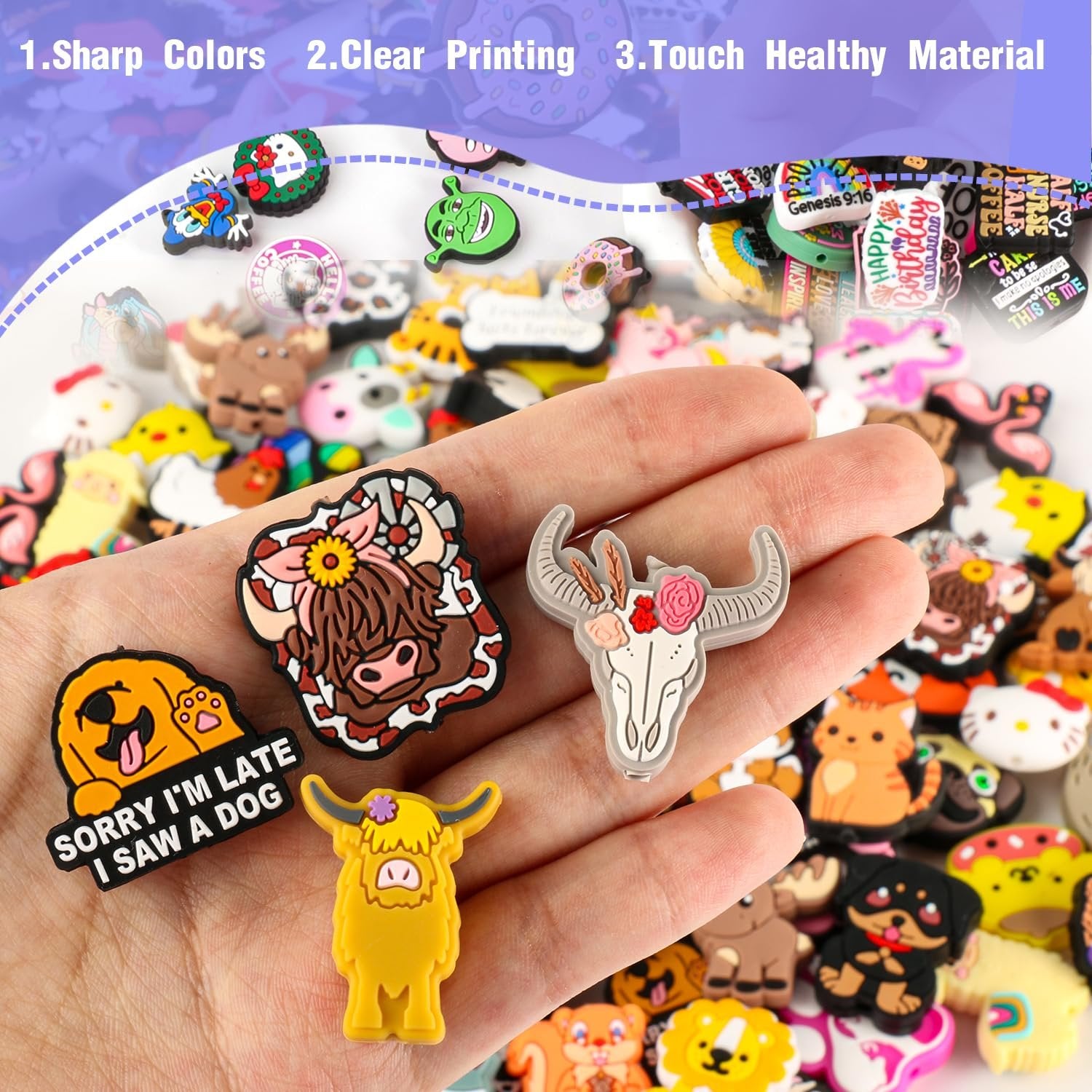 Hand holding various cartoon silicone charms including a highland cow, a dog, and a bull skull. Many more charms are visible in the background.