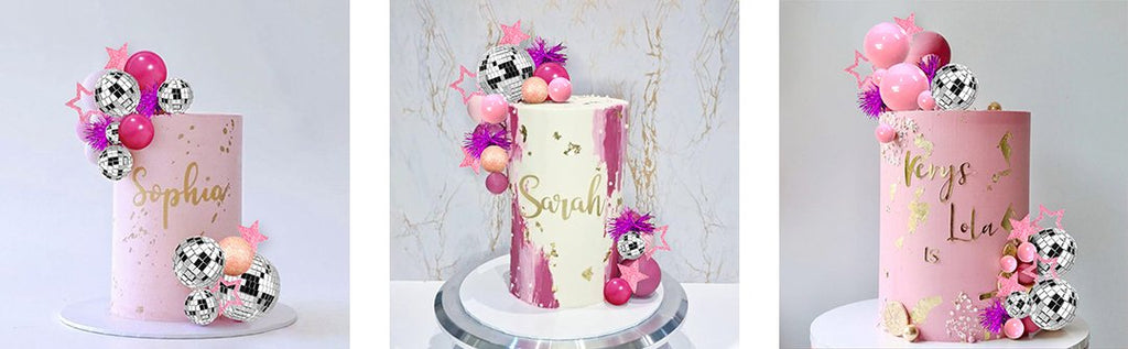 Three pink cakes decorated with disco ball cake toppers, pink balloons, and glitter stars.