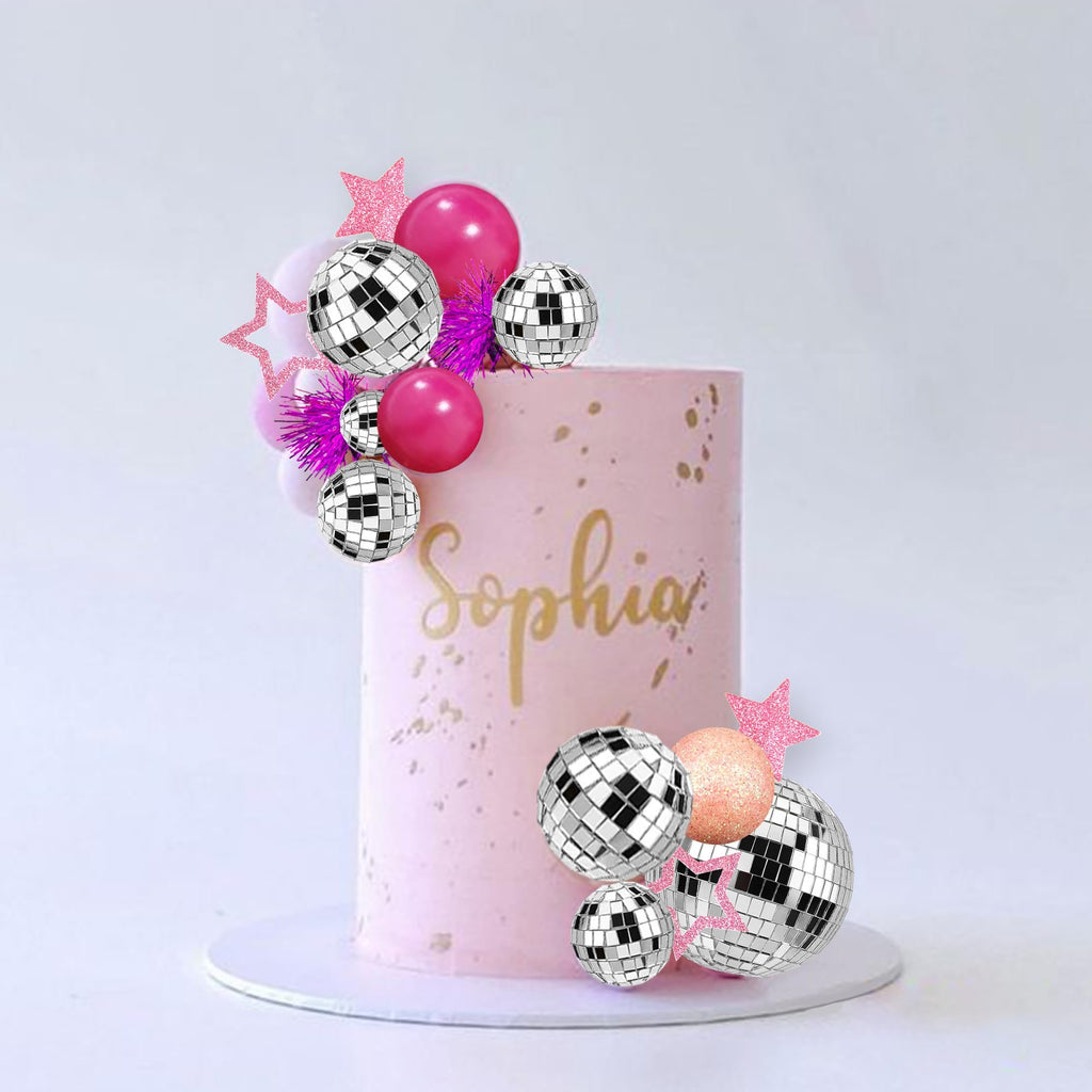 Pink cake decorated with disco ball and star cake toppers, with the name Sophia in gold script.