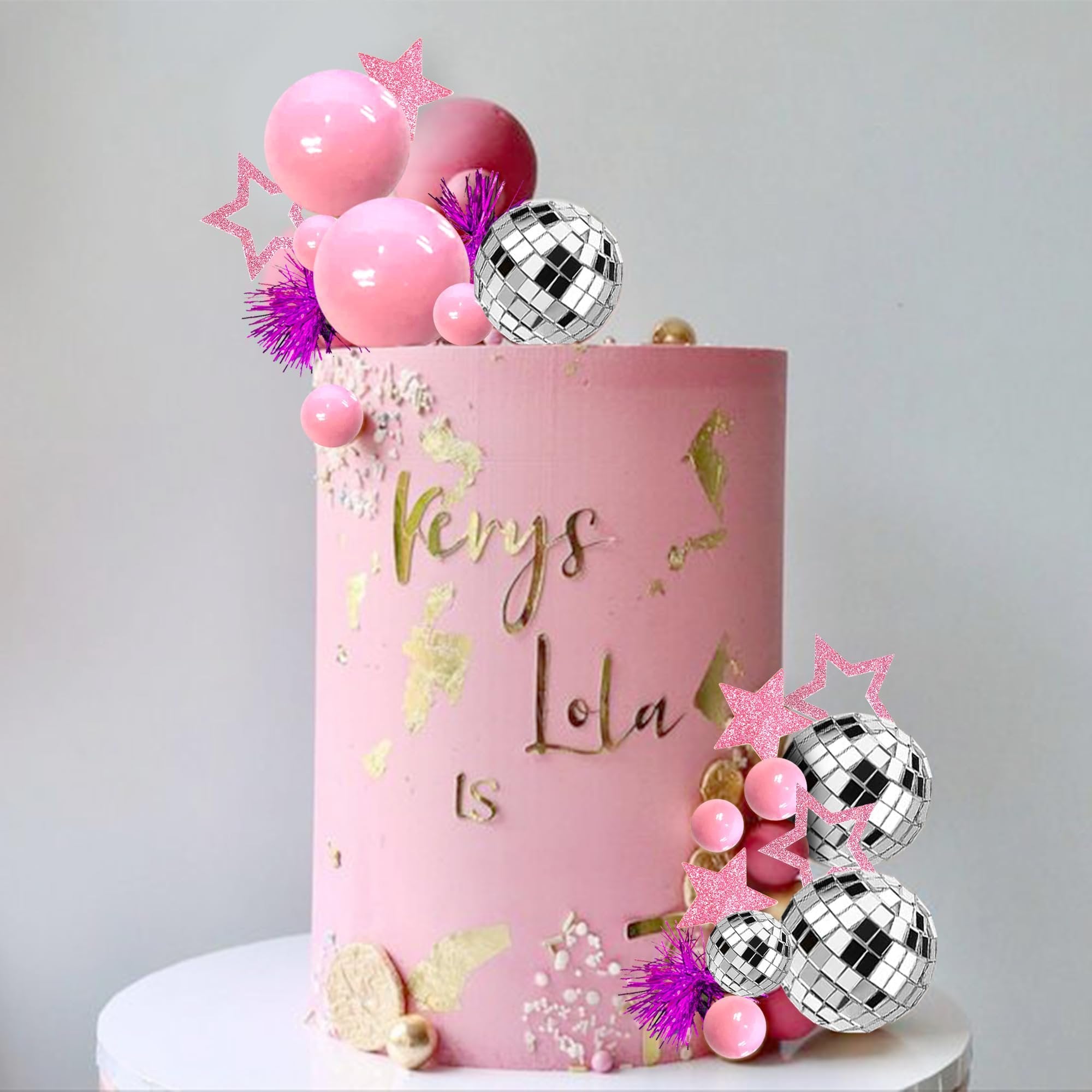 Pink cake decorated with disco ball toppers, pink spheres, glitter stars, and gold leaf accents. Text reads 'Kerys Lola LS'.