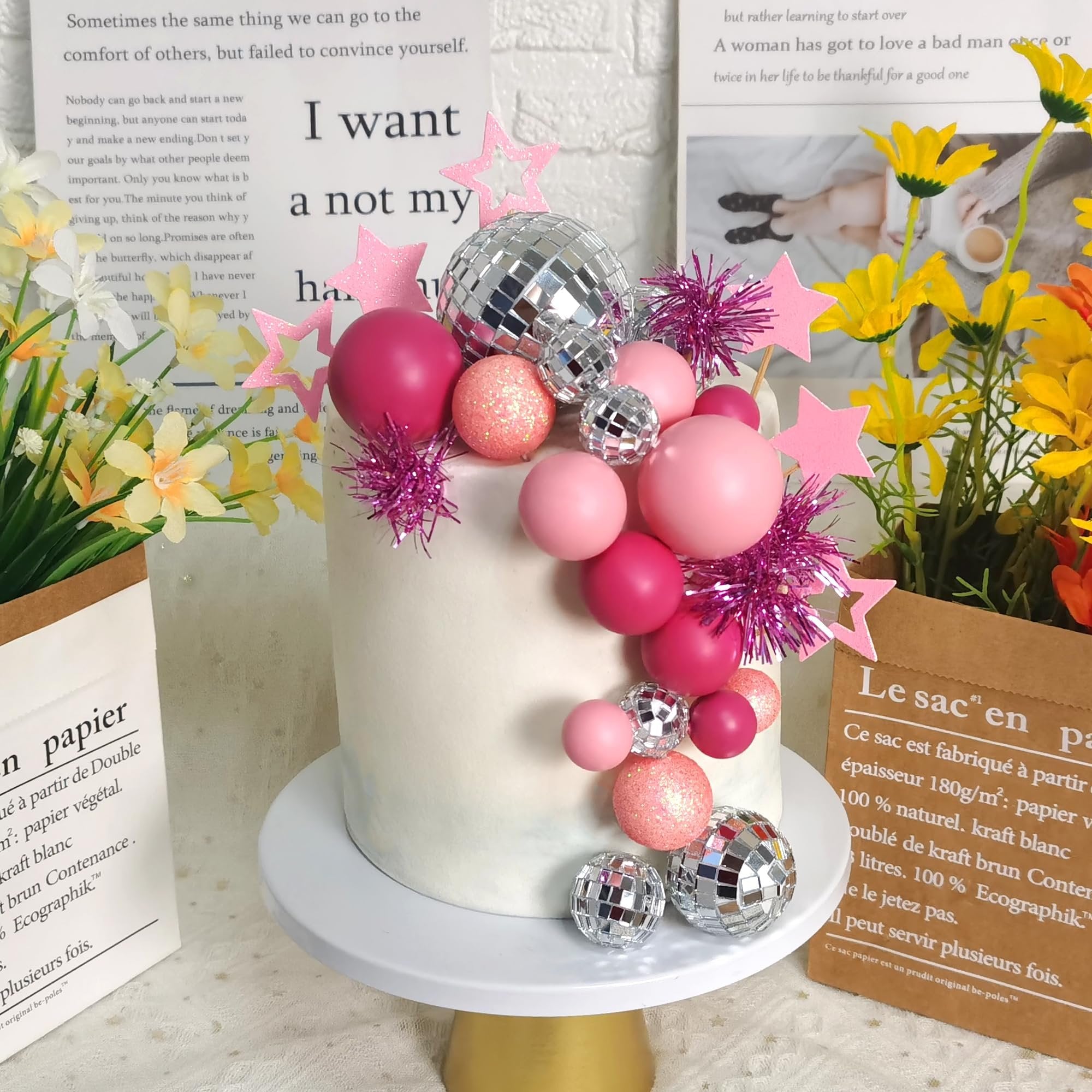 Pink and silver disco ball cake topper set with spheres and stars on a white cake