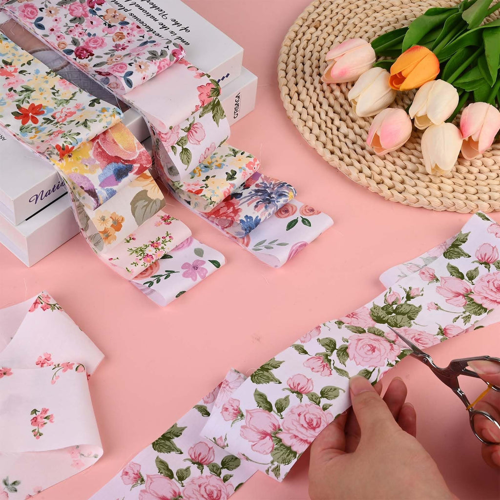 Pink retro floral cotton fabric strips being cut with scissors, with tulips and books in the background.