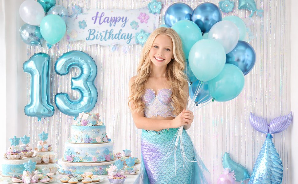 Girl in mermaid costume holding balloons at a 13th birthday party with ocean-themed cake and cupcakes