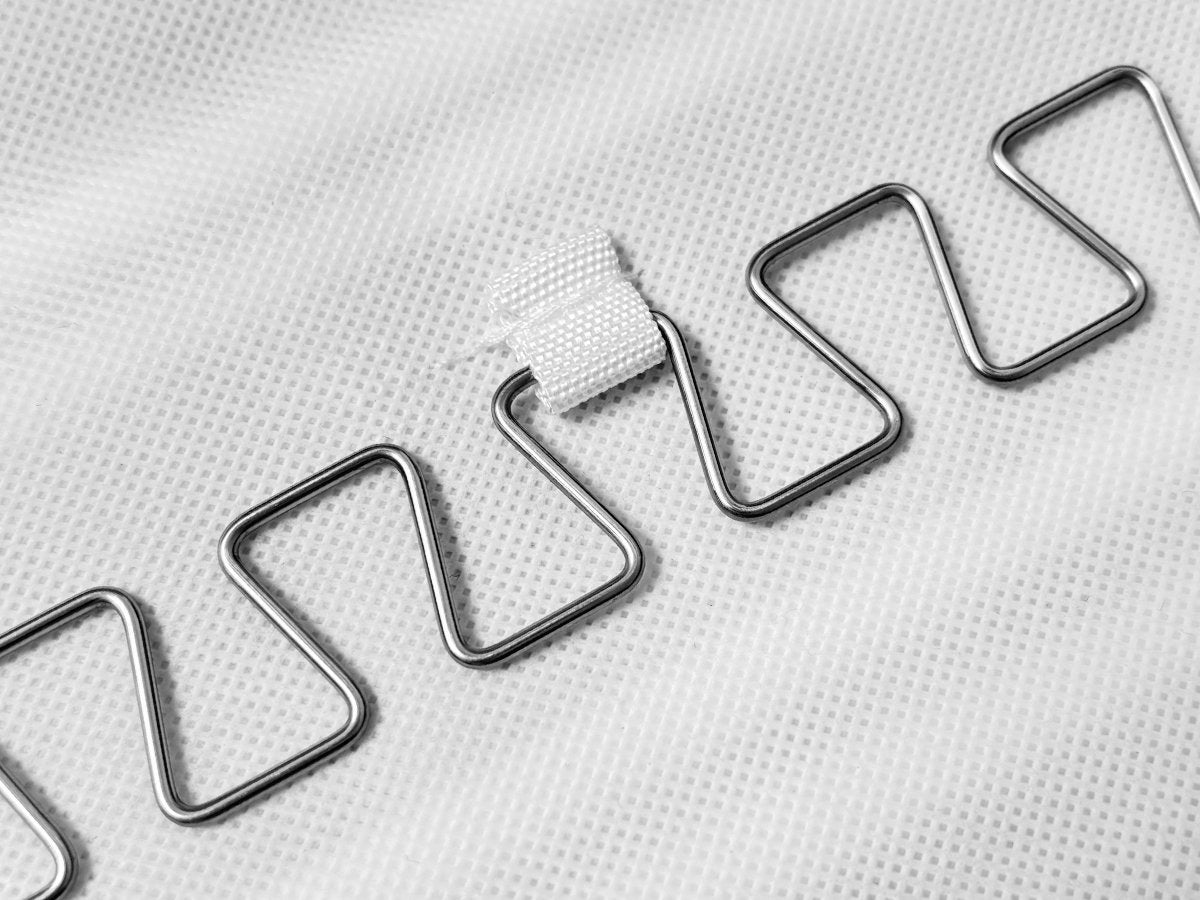 Close-up of metal hooks on white fabric, part of a hanging jewelry organizer.