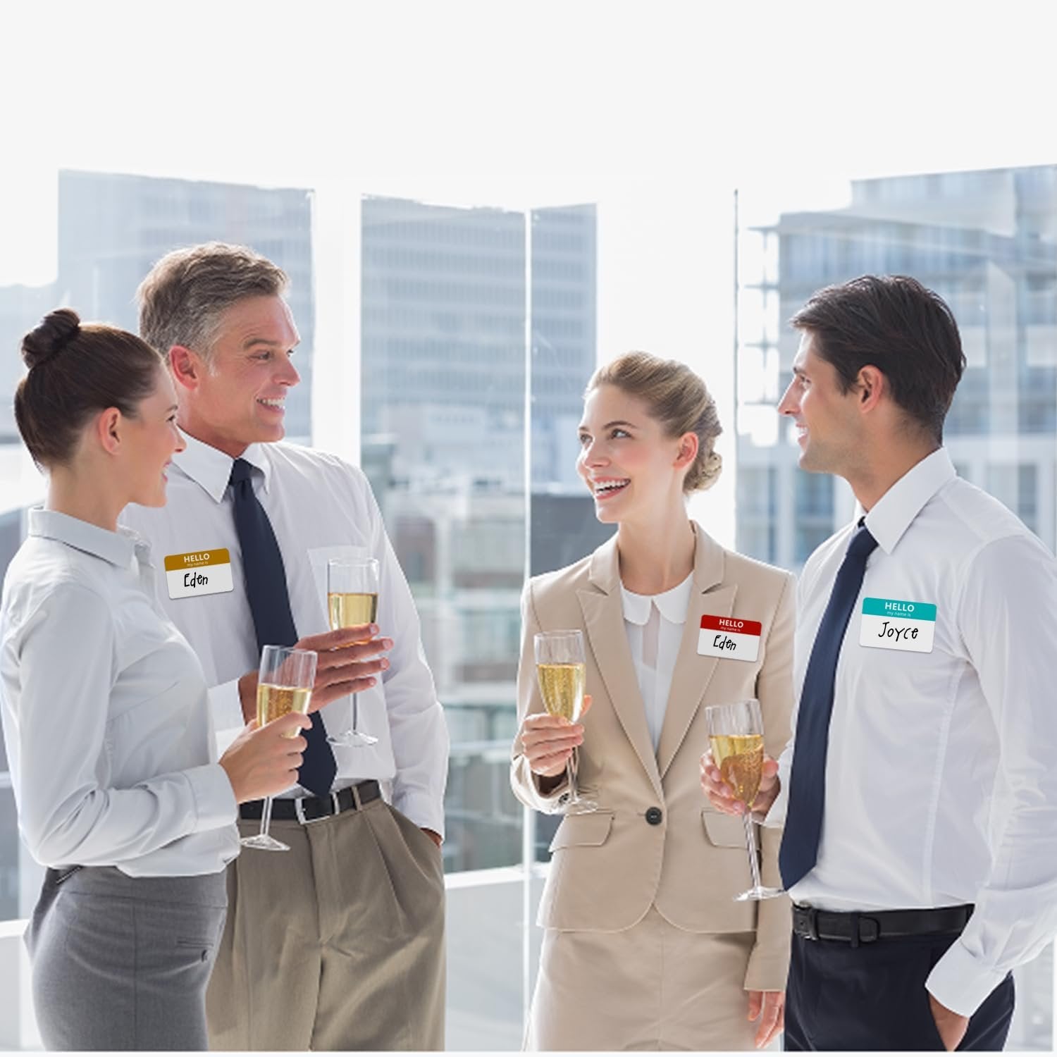 Four professionals in business attire holding champagne flutes at a networking event, wearing name tags.