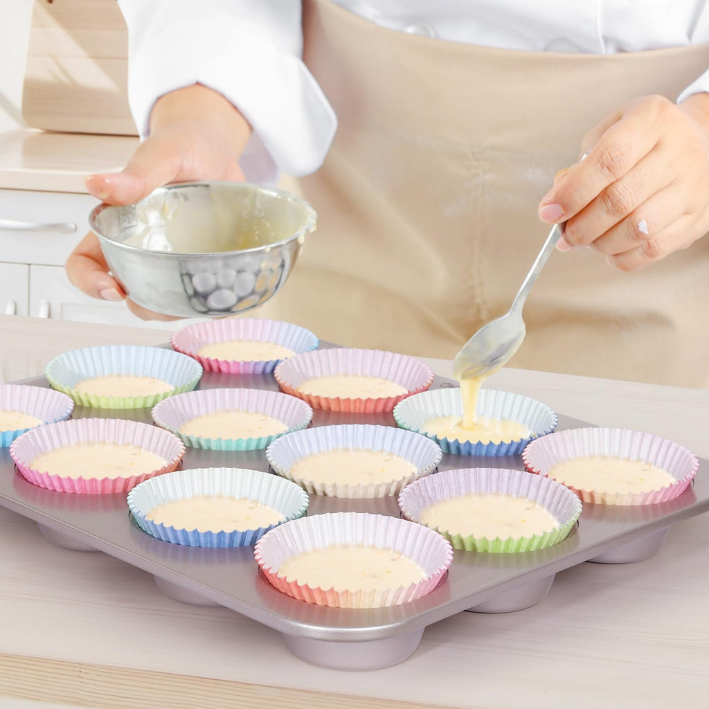 Person pouring cupcake batter into colorful paper liners in a muffin tin