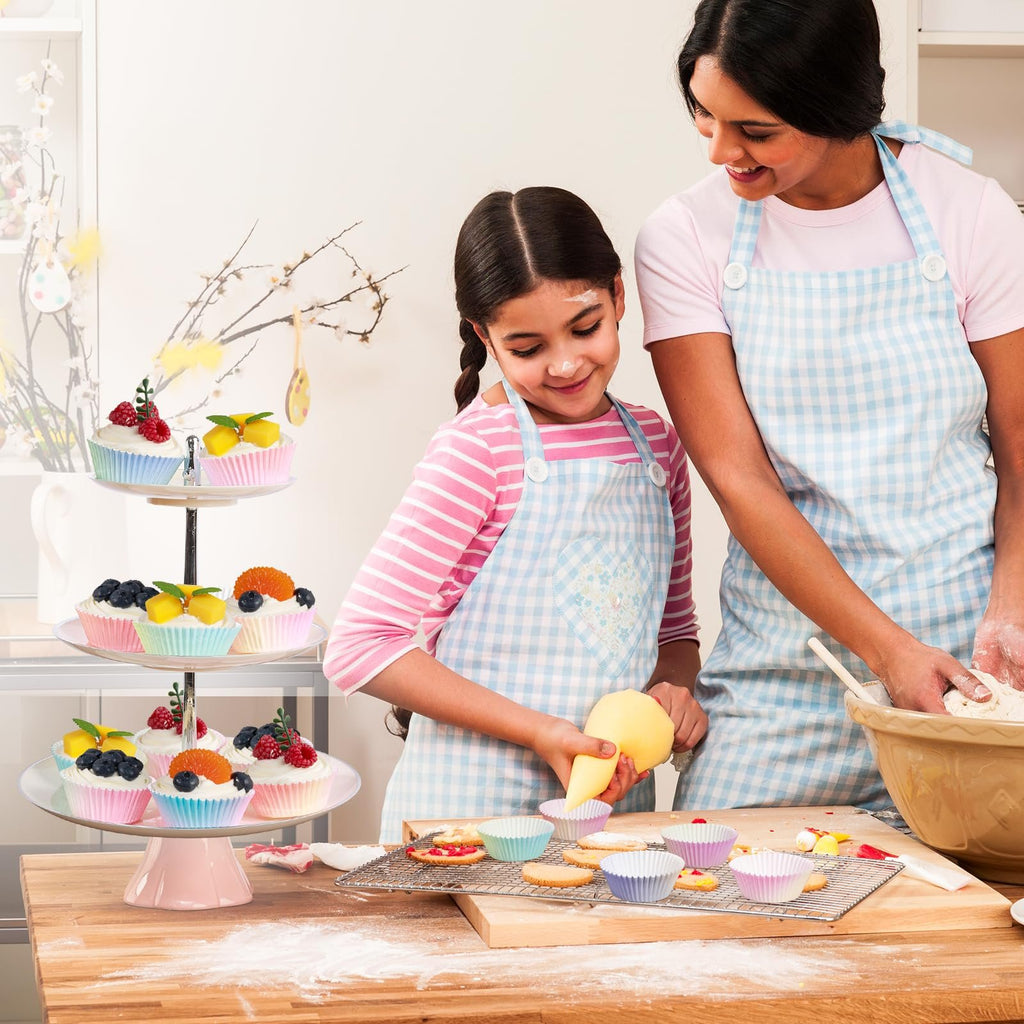 Mother and daughter baking cupcakes together, with a tiered stand displaying decorated cupcakes.