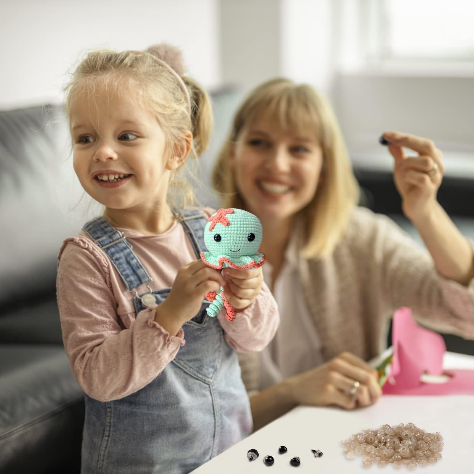 Young girl holding a crocheted octopus toy while a woman in the background holds a safety eye