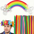 Man wearing a balloon flower crown with a rainbow balloon arch and a bundle of colorful twisting balloons