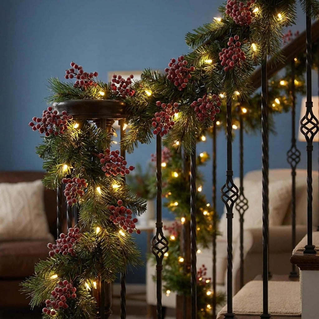 Christmas garland with frosted holly berries and warm white lights draped on a staircase railing