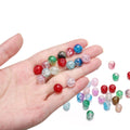 Hand holding various colorful crackle glass beads for jewelry making