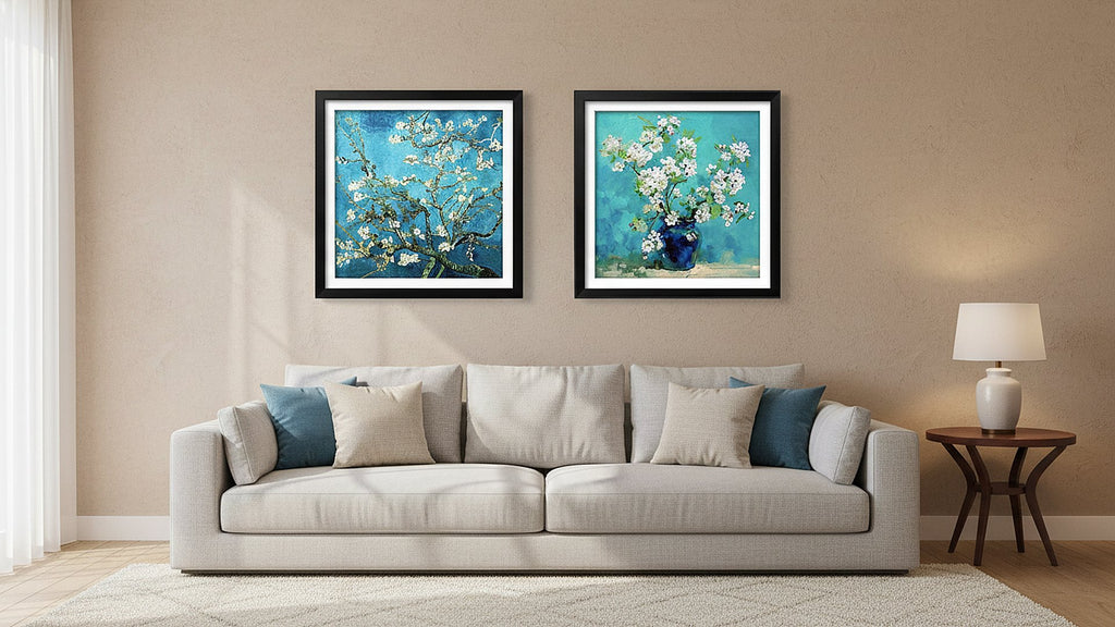 Two framed floral paintings hanging above a sofa with decorative pillows and a side table with a lamp.