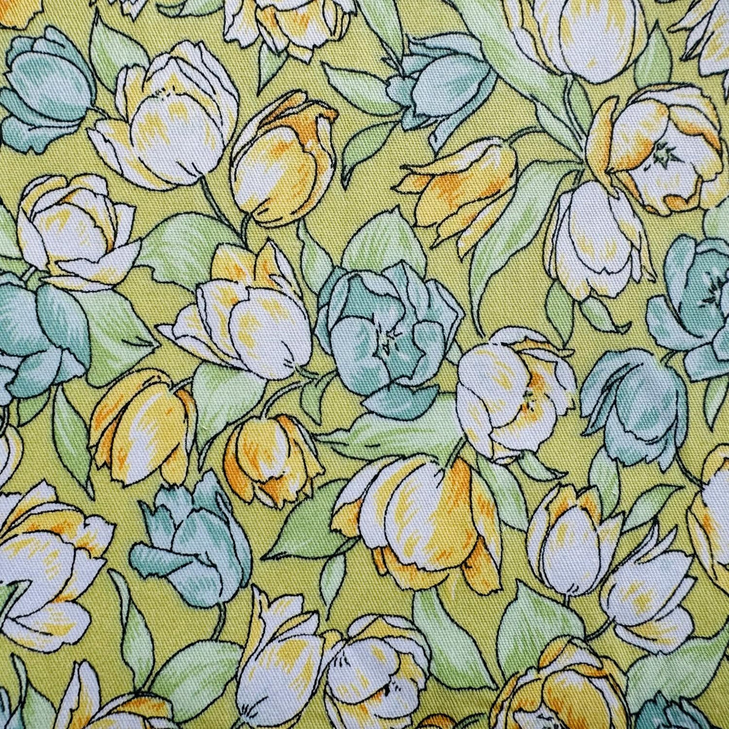 Close-up of yellow, white, and teal floral pattern on a light green fabric background.