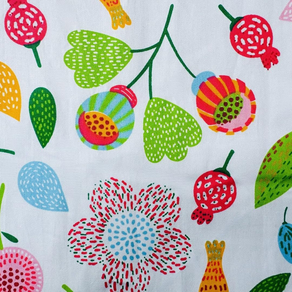 Close-up of white cotton fabric with a repeating pattern of colorful floral and leaf motifs.