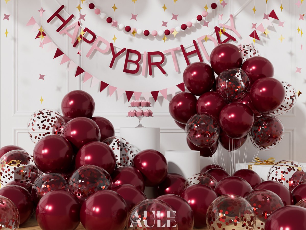 Burgundy and confetti balloons arranged with a 'Happy Birthday' banner and decorative garlands for a party setting.