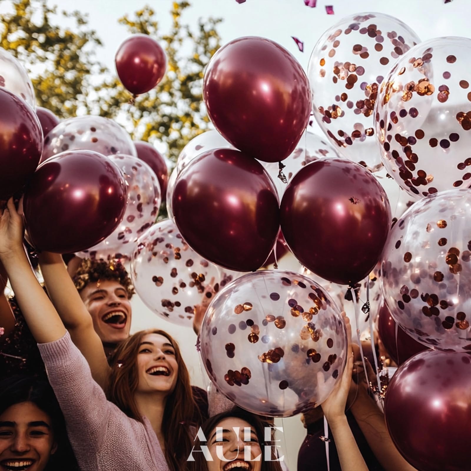 Group of happy people holding burgundy and confetti balloons outdoors