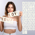 Woman holding stencils spelling HOME and LOVE, with a grid of alphabet and number stencils in the background.