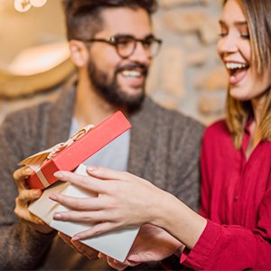 Couple opening a red and white gift box with a ribbon
