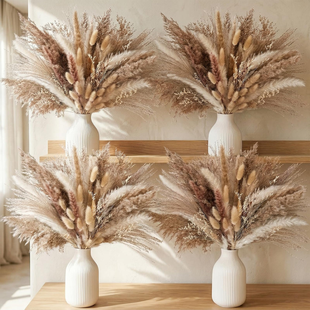 Four vases filled with dried pampas grass and bunny tail decor arranged on a wooden shelf and table.