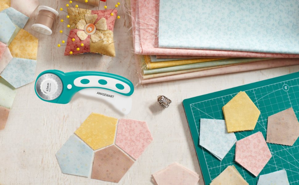 Turquoise rotary cutter and fabric cutting mat with fabric scraps and sewing notions on a light wooden surface.