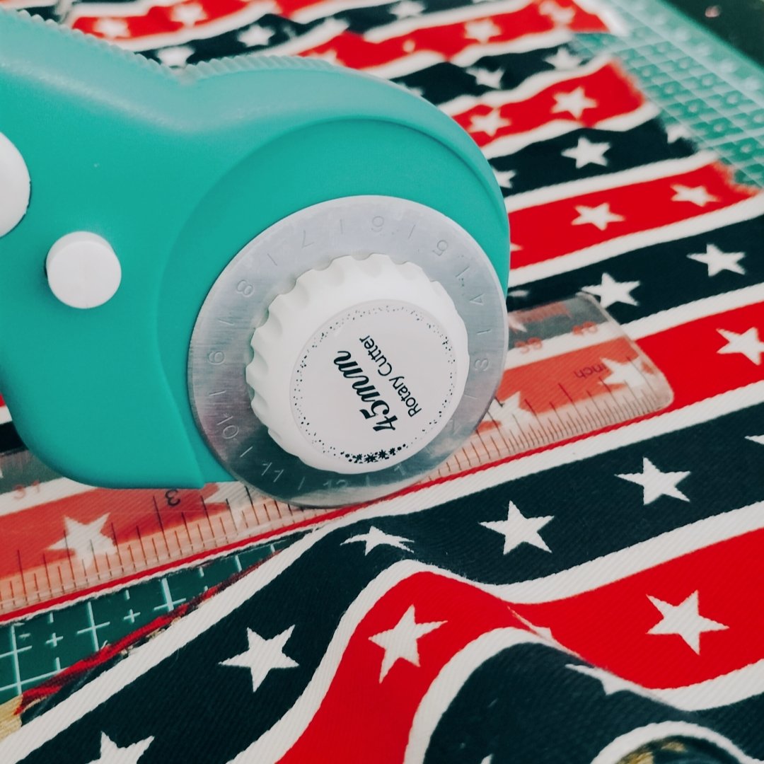 Teal rotary cutter with 45mm blade on patriotic fabric with ruler