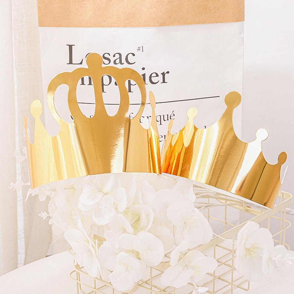 Two gold paper crowns displayed in a decorative basket with white flowers, with a paper bag in the background.
