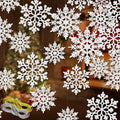 White glitter snowflake ornaments of various sizes hanging with spools of silver and gold rope on a blurred background.