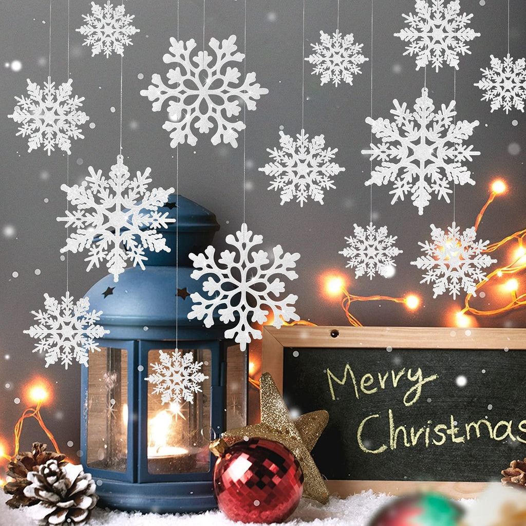 White glitter snowflake ornaments hanging near a blue lantern and a Merry Christmas chalkboard