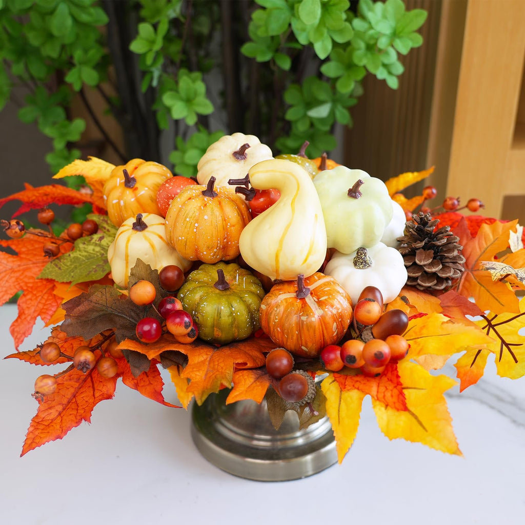 Fall harvest decor arrangement with assorted artificial pumpkins, gourds, pinecones, berries, and maple leaves in a metallic vase.