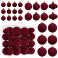 Burgundy flocked velvet Christmas ball ornaments in assorted sizes and textures, displayed in a clear box and scattered around.