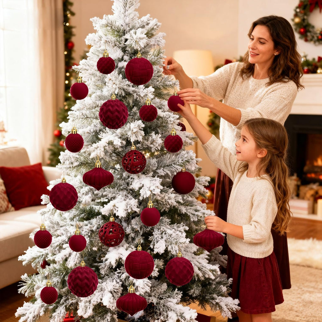 Woman and child decorating a flocked Christmas tree with burgundy ornaments