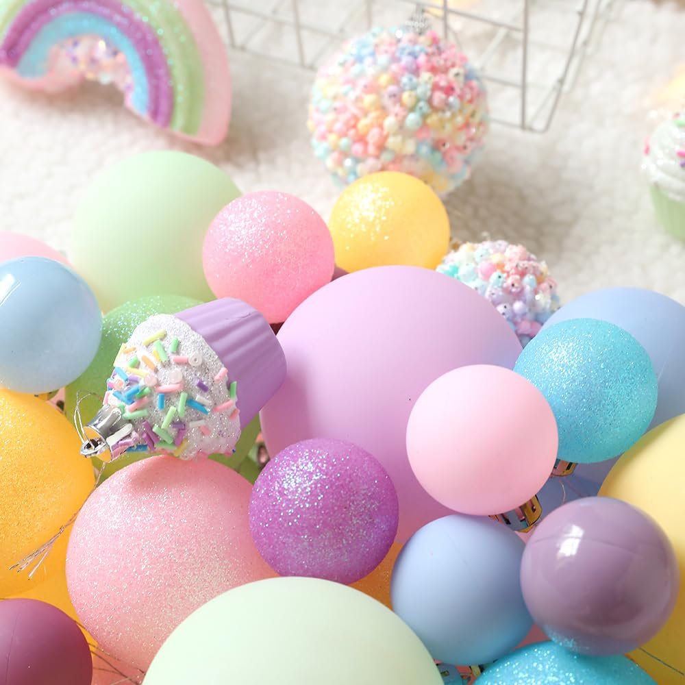 Assortment of pastel Christmas ornaments including balls, rainbows, and cupcake shapes.