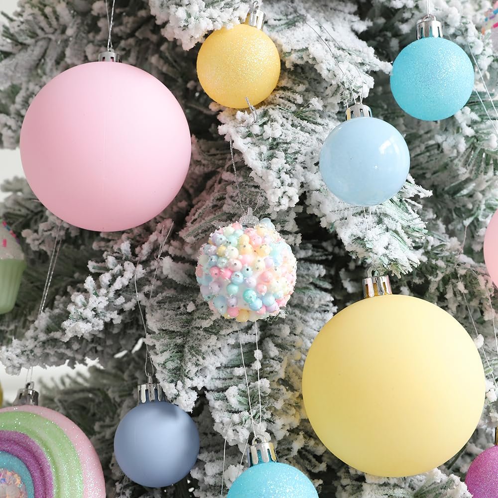 Pastel Christmas ornaments in various shapes and sizes hanging on a flocked tree branch.