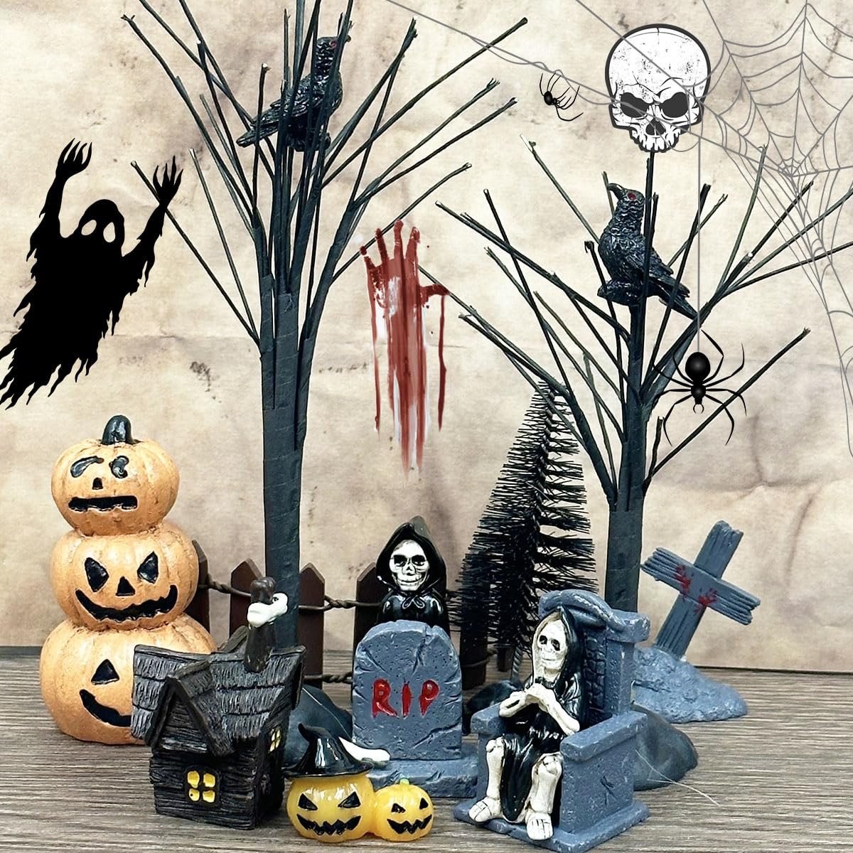 Halloween village scene with stacked pumpkins, spooky house, grim reapers, tombstones, crows, spiders, and a skull decoration.