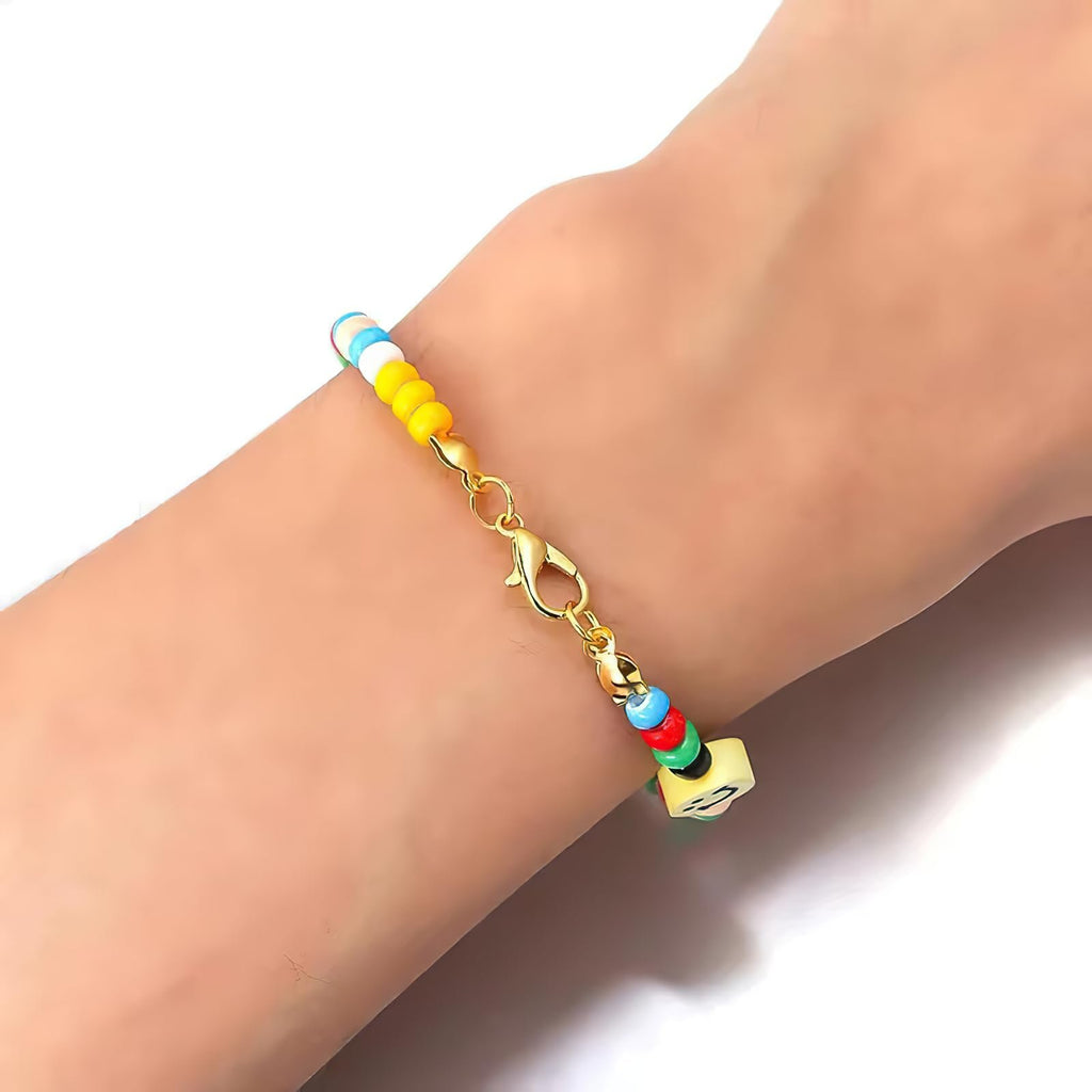 Close-up of a colorful beaded bracelet with a gold lobster claw clasp on a wrist against a white background.
