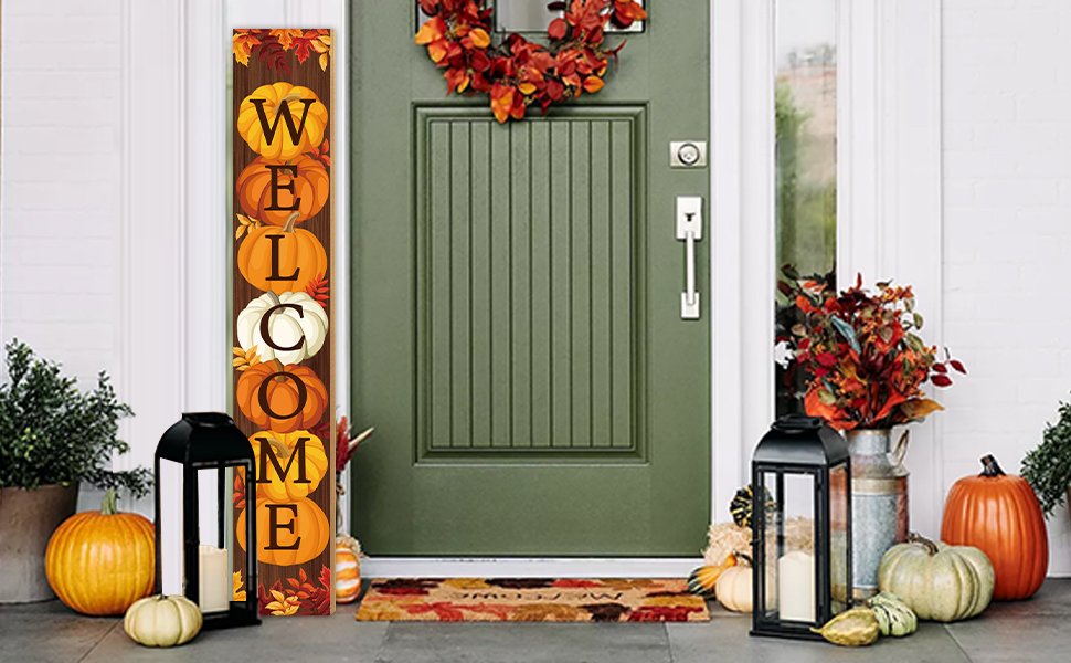 Vertical fall porch sign with pumpkins spelling 'WELCOME' next to a green door and autumn decorations.