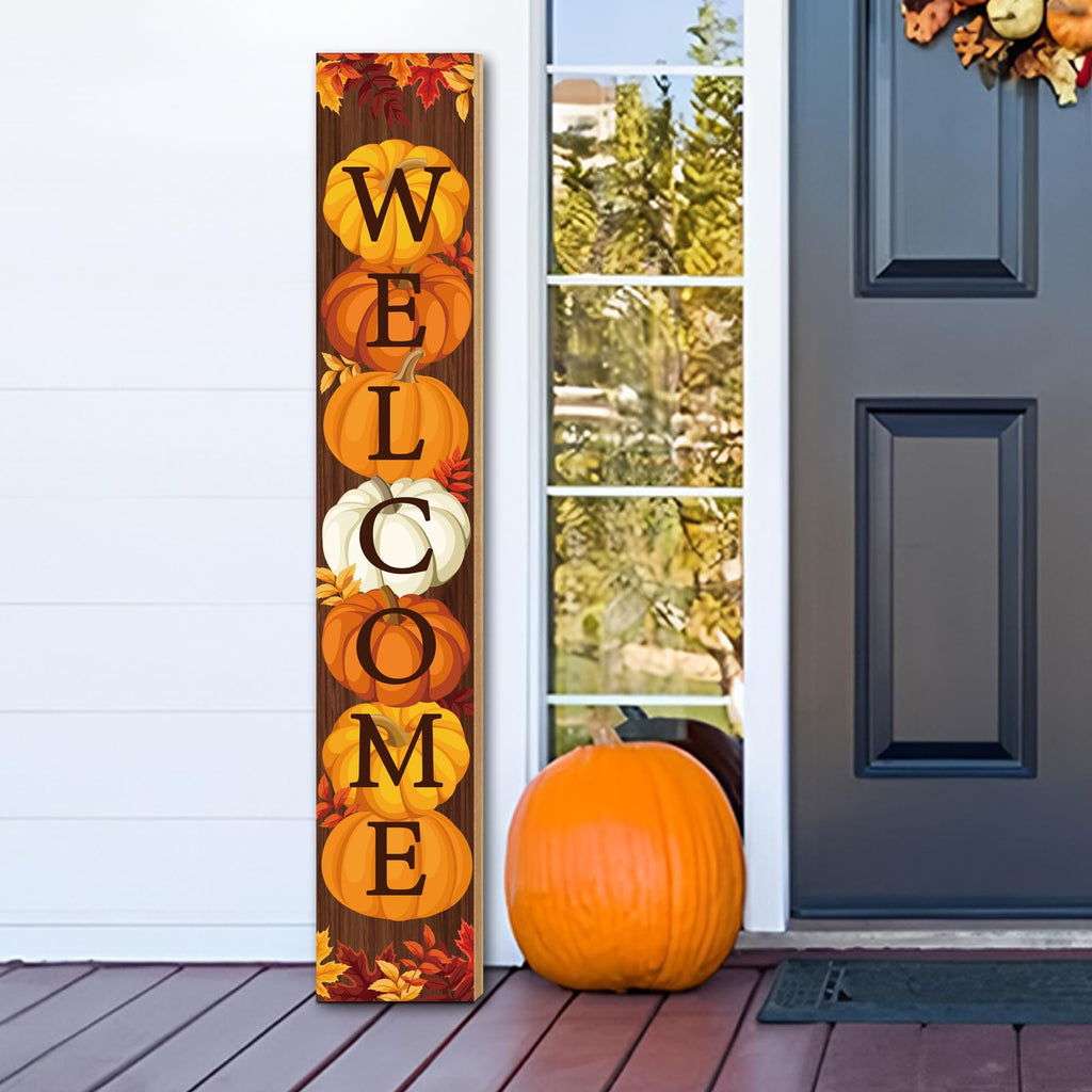 Vertical fall porch sign with pumpkins spelling WELCOME, decorated with autumn leaves, placed on a porch next to a real pumpkin.