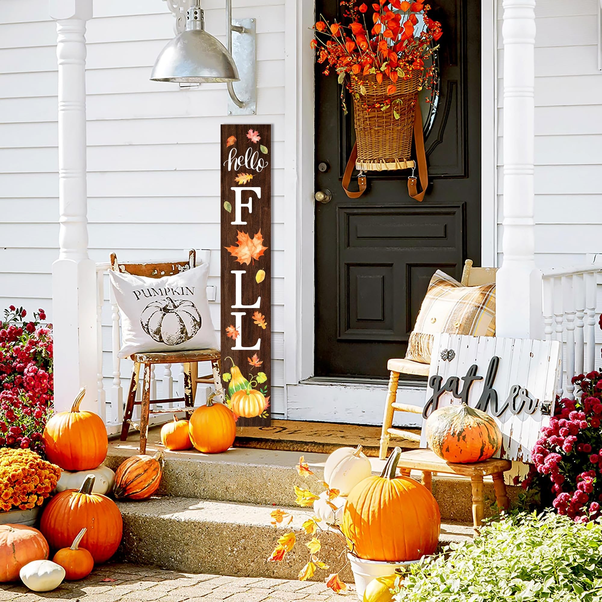 Wooden porch sign with 'hello FALL' text and autumn leaves, decorated with pumpkins and gourds on a porch with chairs and pumpkins.