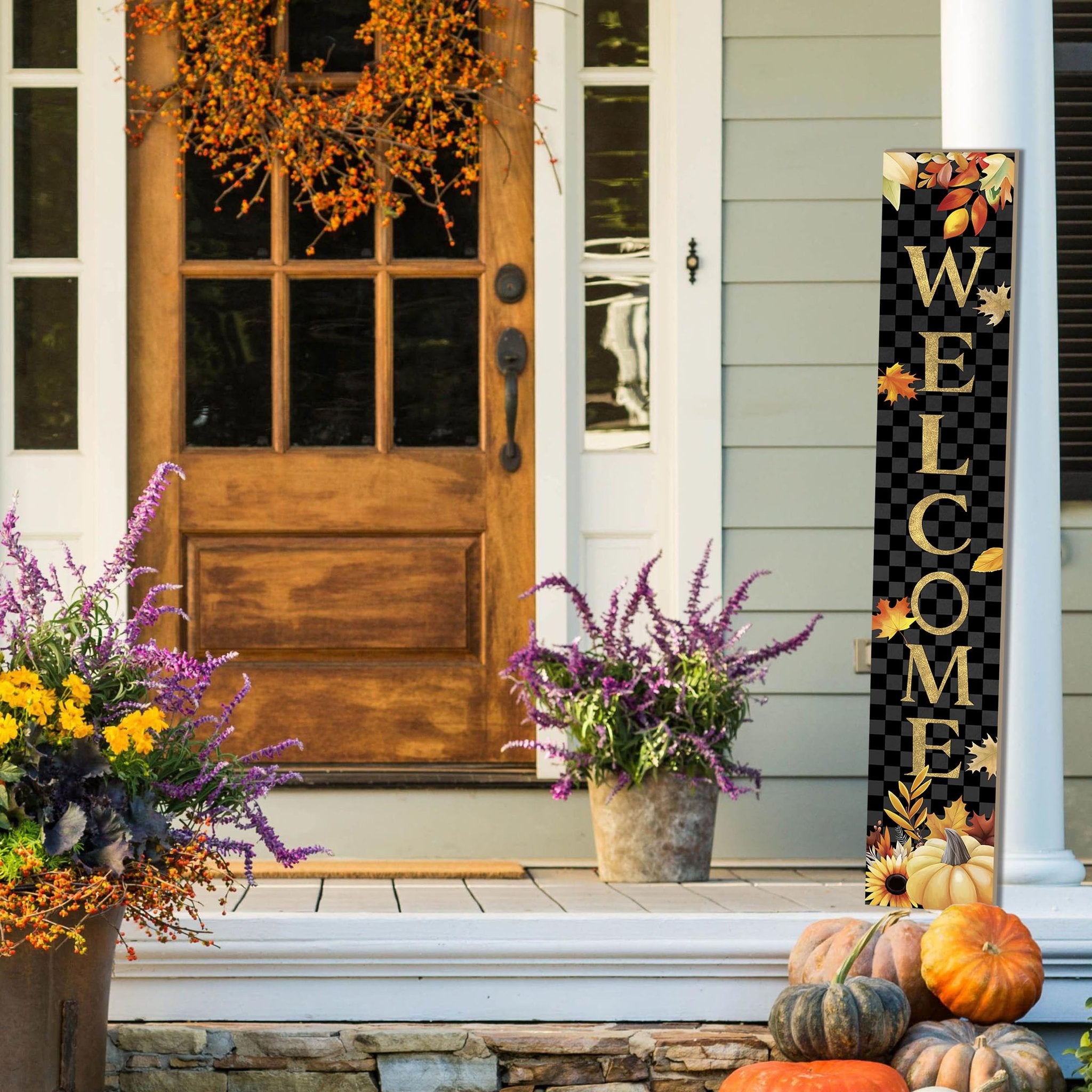Vertical autumn porch sign with 'WELCOME' text and fall leaves, standing on a porch with pumpkins and plants.