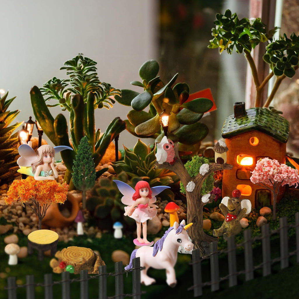 Miniature fairy garden scene with figurines, trees, house, and moss. Includes fairies, unicorn, owl, frog, and decorative plants.