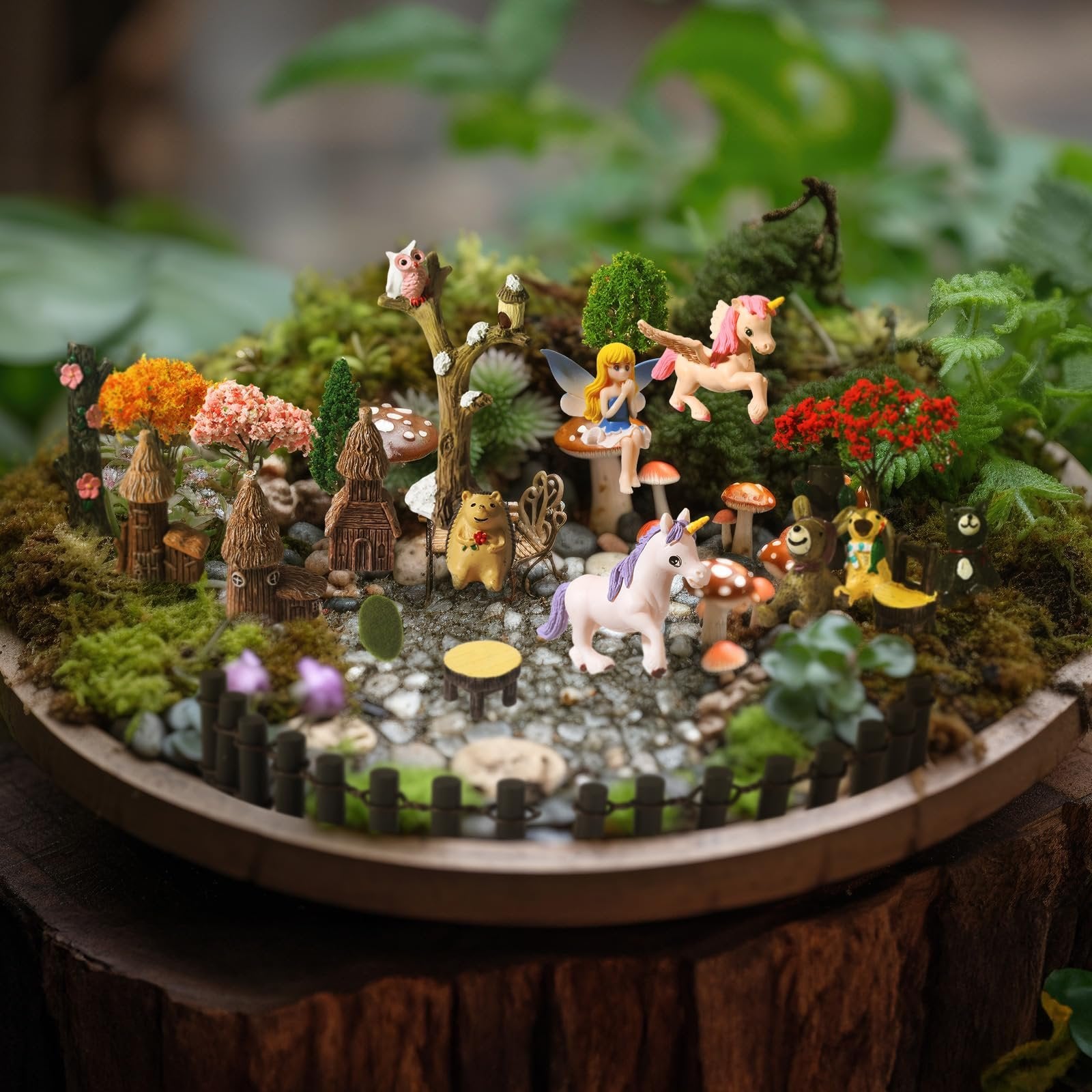 Miniature fairy garden scene with unicorns, fairies, animals, houses, trees, and moss on a wooden base.