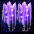 Two light-up hanging ghost decorations with purple LEDs, displayed outdoors at night.