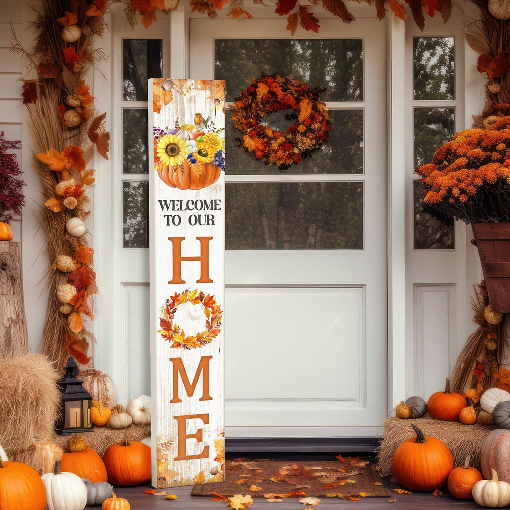 Vertical porch sign with pumpkin and sunflowers saying WELCOME TO OUR HOME, decorated for fall with pumpkins and autumn leaves.