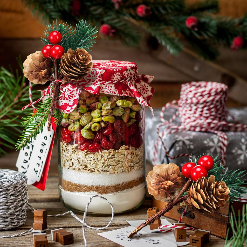 Layered cookie mix in a jar with Christmas decorations, pine cones, and red berries.