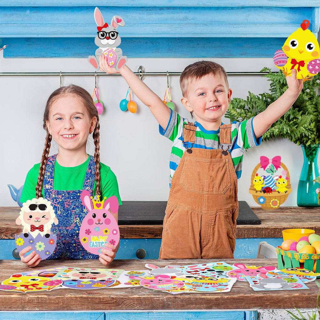 Two smiling children hold up Easter craft cutouts, with more craft supplies laid out on a wooden table.