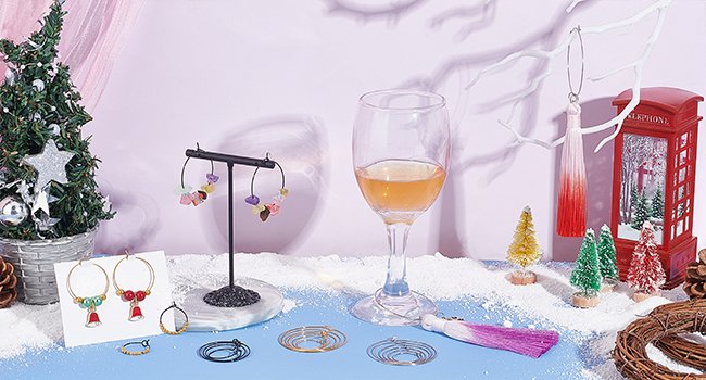 Jewelry making supplies including hoop earrings, jump rings, and tassels arranged on a blue surface with a festive winter theme.